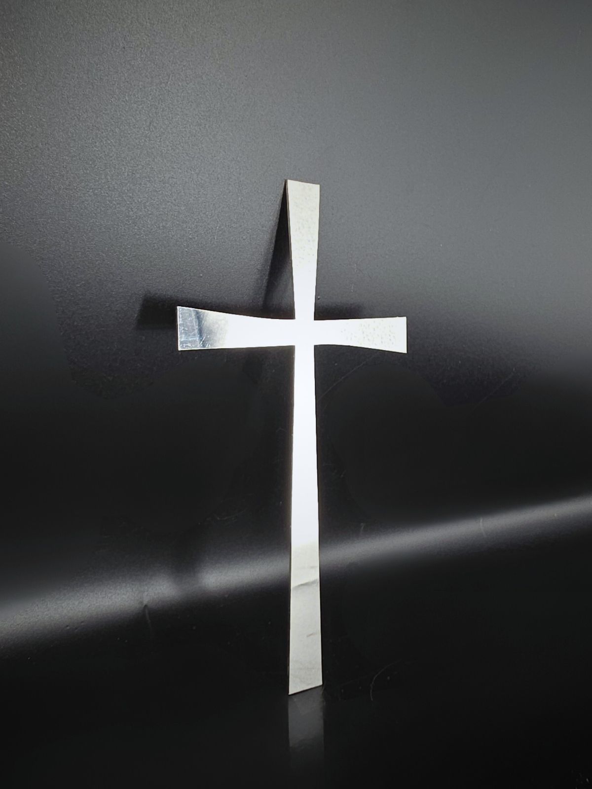 Zdjęcie przedstawia wykonany ze stali nierdzewnej krzyż wycinany laserowo.