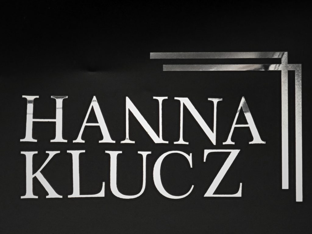 Zdjęcie przedstawia litery nagrobne ułożone wpoglądowe imię i nazwisko "Hanna Klucz". W prawym górnym rogu jest ozdoba.